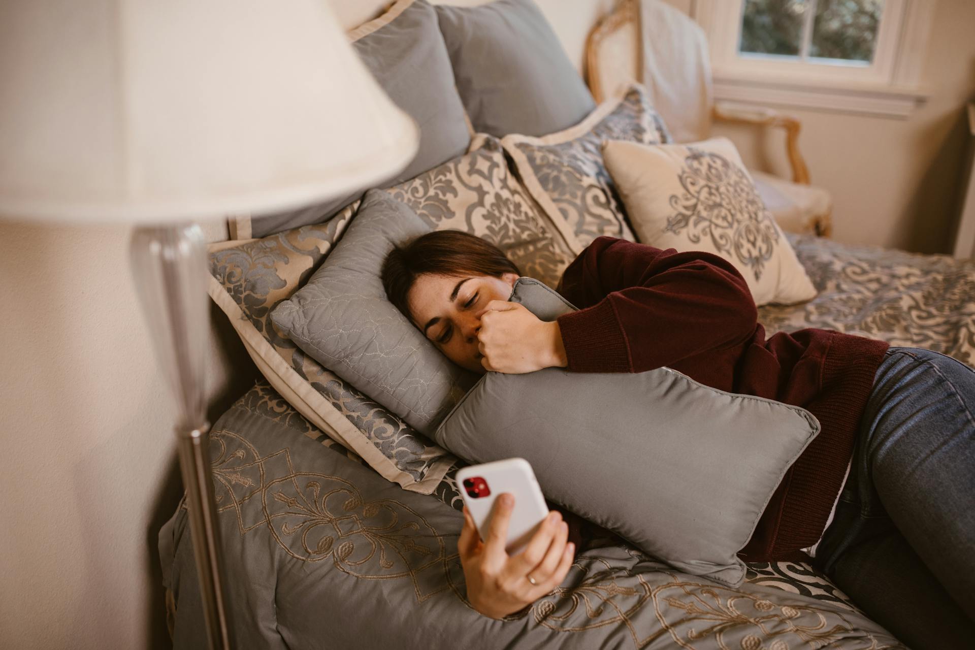 Una mujer viendo su smartphone tumbada en la cama | Fuente: Pexels