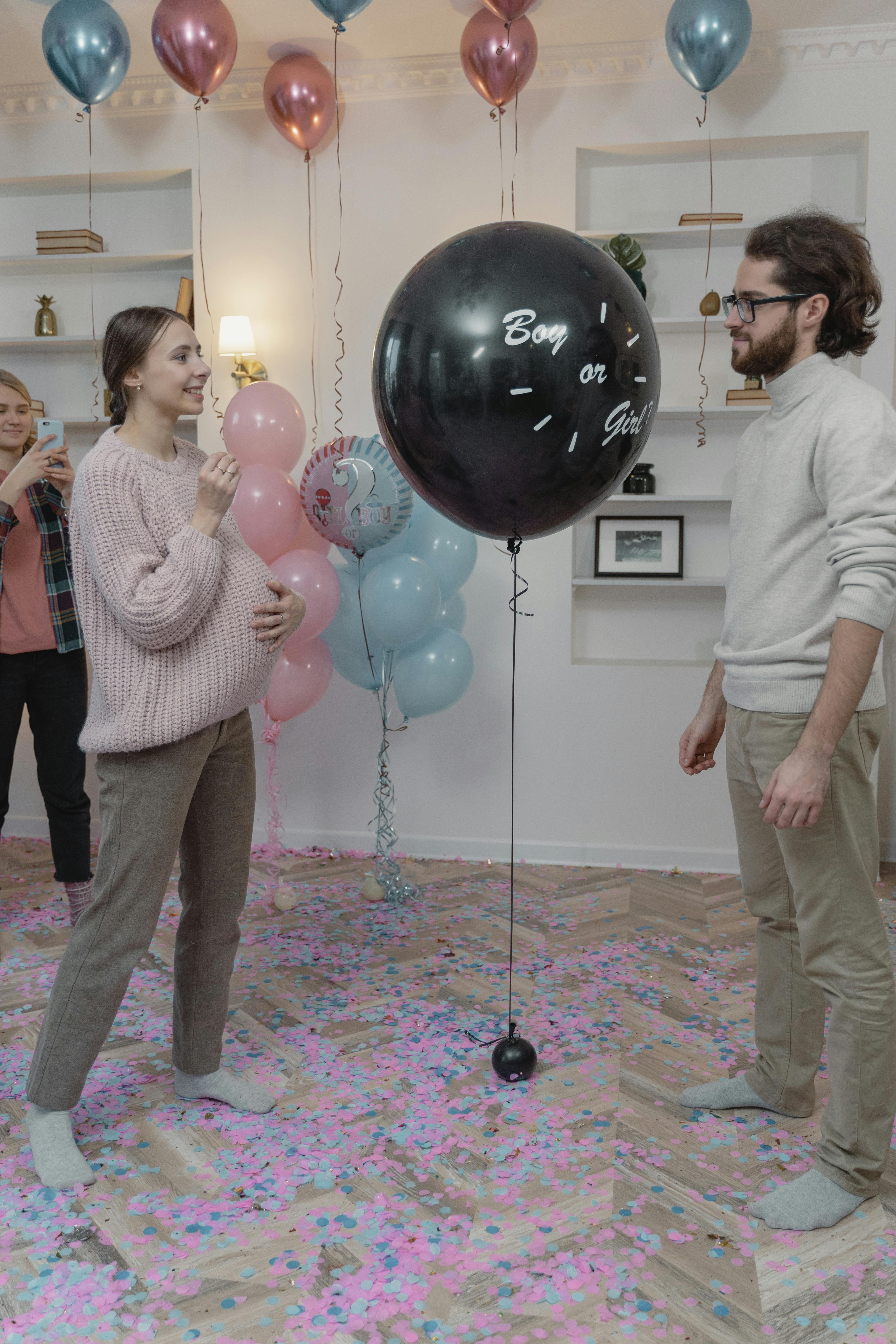 Una pareja a punto de explotar un globo en una fiesta de revelación de sexo | Fuente: Pexels