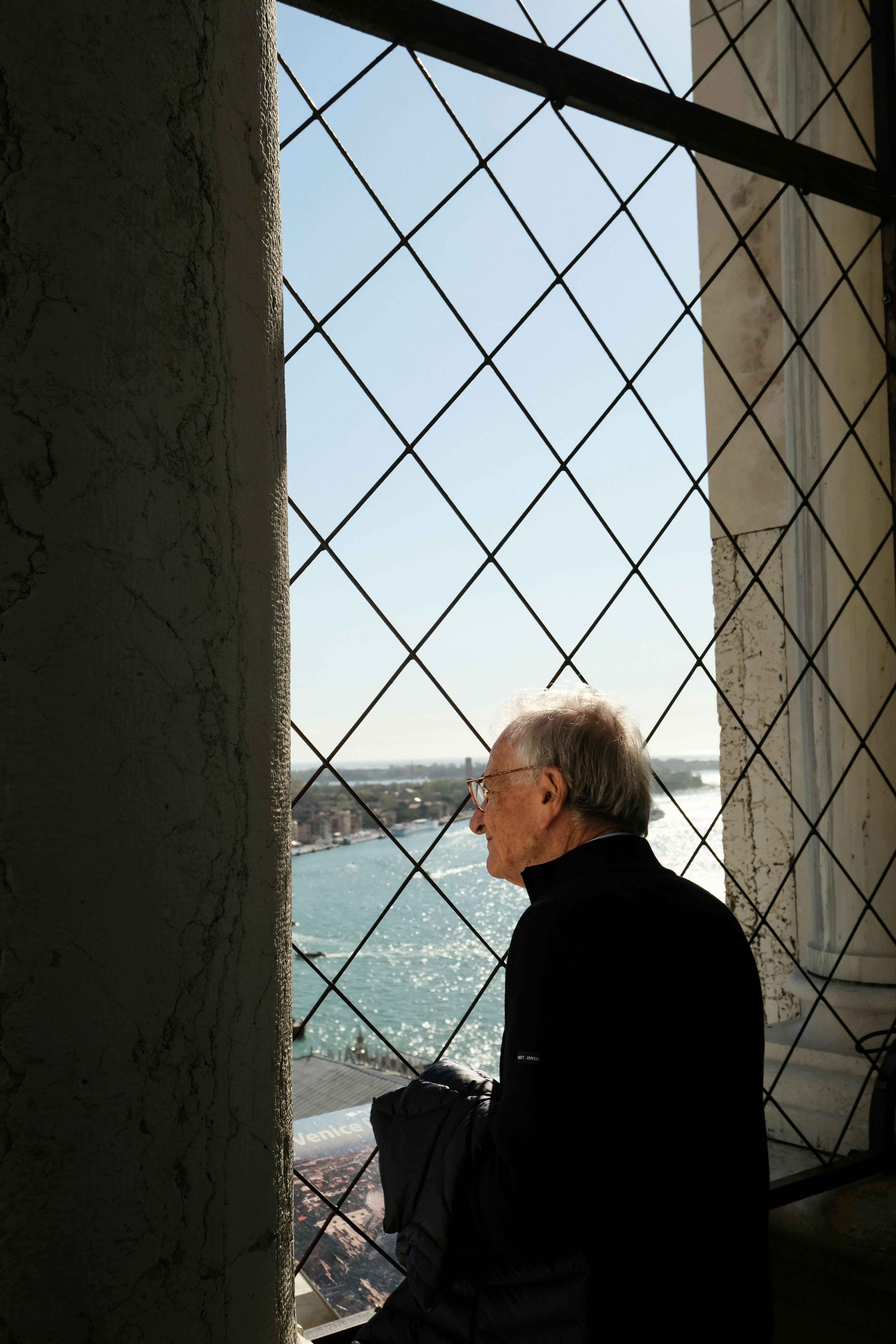 Anciano mirando por una ventana | Fuente: Pexels
