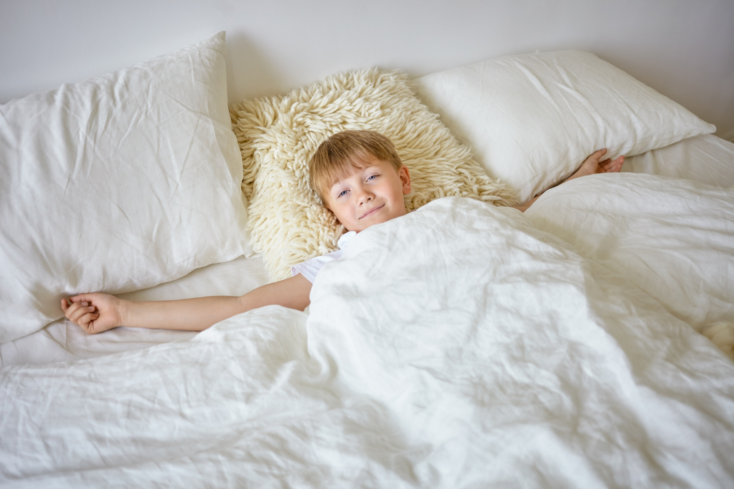 Un niño alegre sonriendo desde su cama | Fuente: Freepik