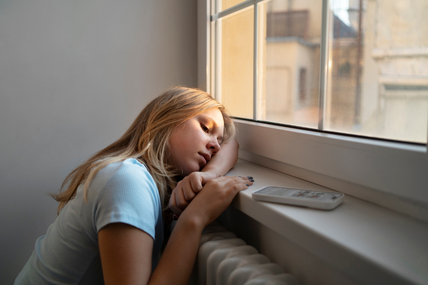 Una adolescente triste sentada junto a la ventana | Fuente: Freepik