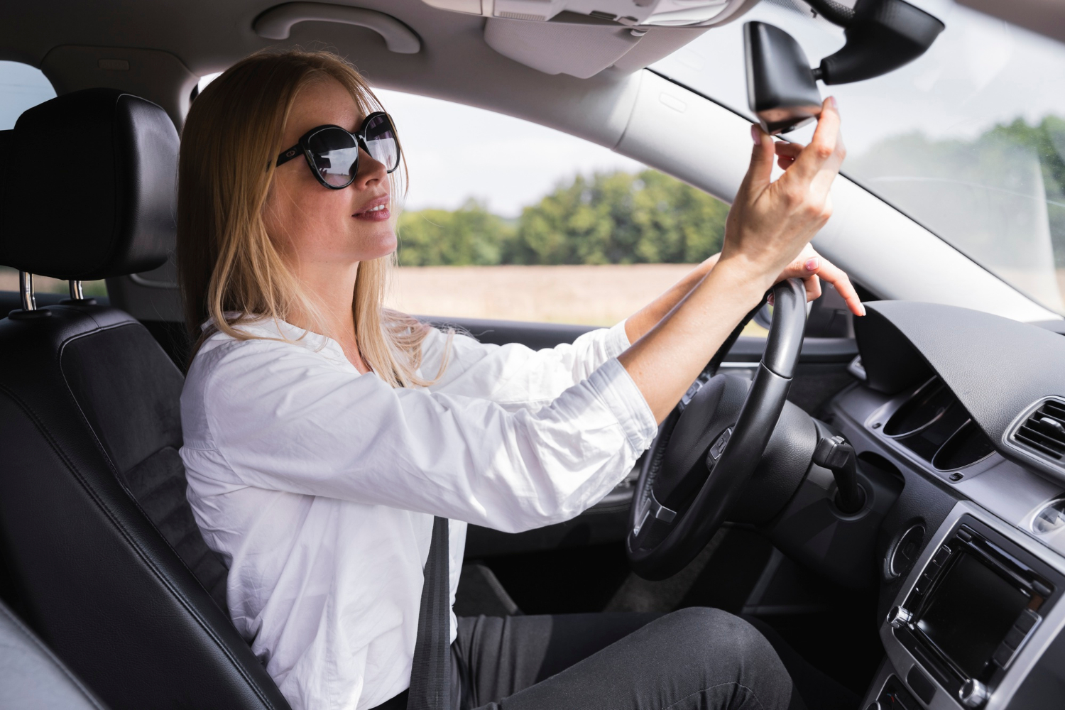 Una mujer en su automóvil ajusta el espejo retrovisor | Fuente: Freepik