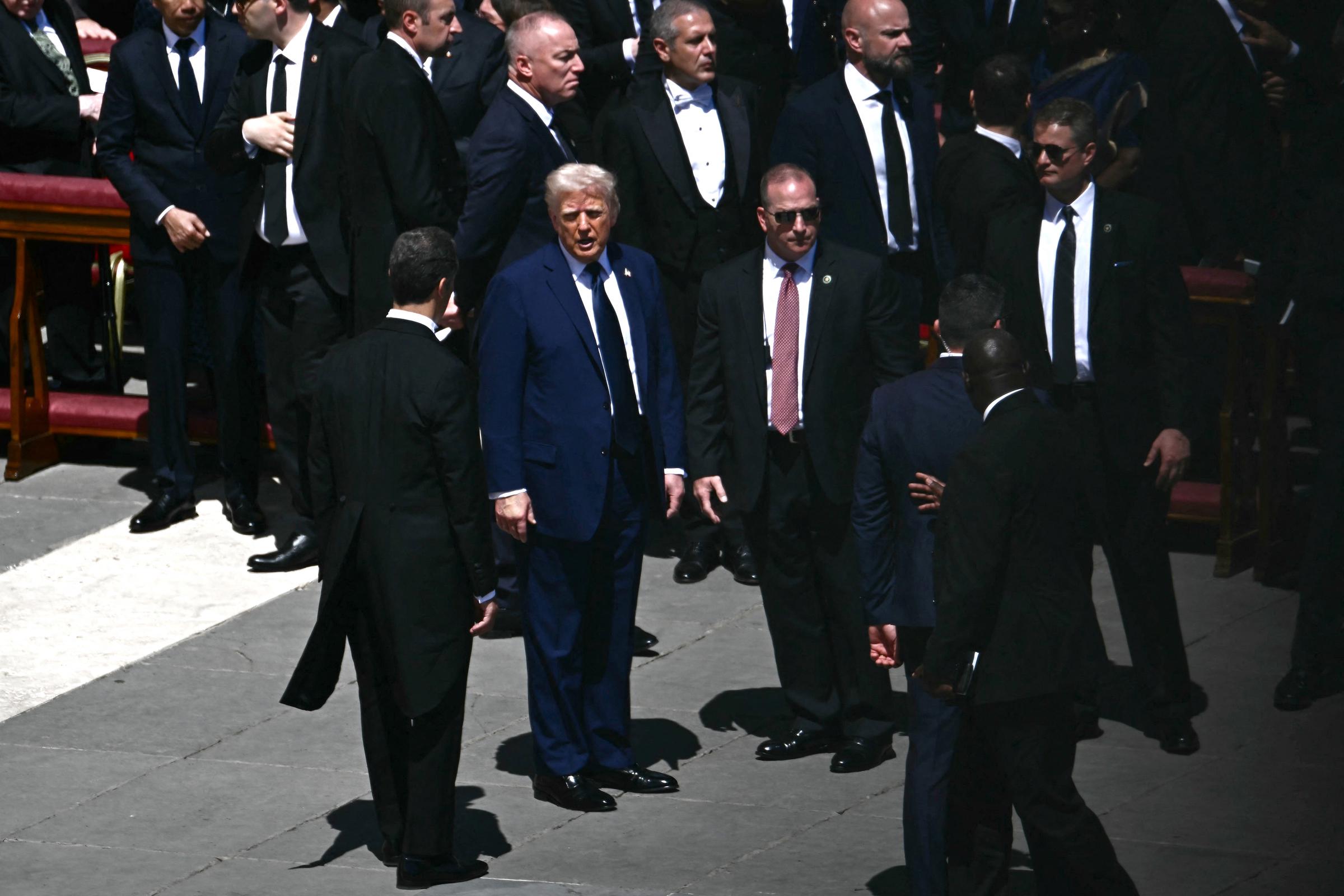 Donald habla con funcionarios tras la ceremonia fúnebre del papa Francisco. Los funcionarios, cada uno vestido de negro, parecen alerta y atentos entre la gran multitud de más de 200.000 personas,