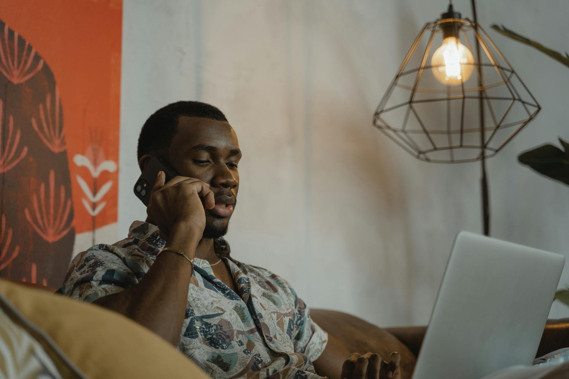 Un hombre mirando su portátil mientras habla por teléfono | Fuente: Pexels