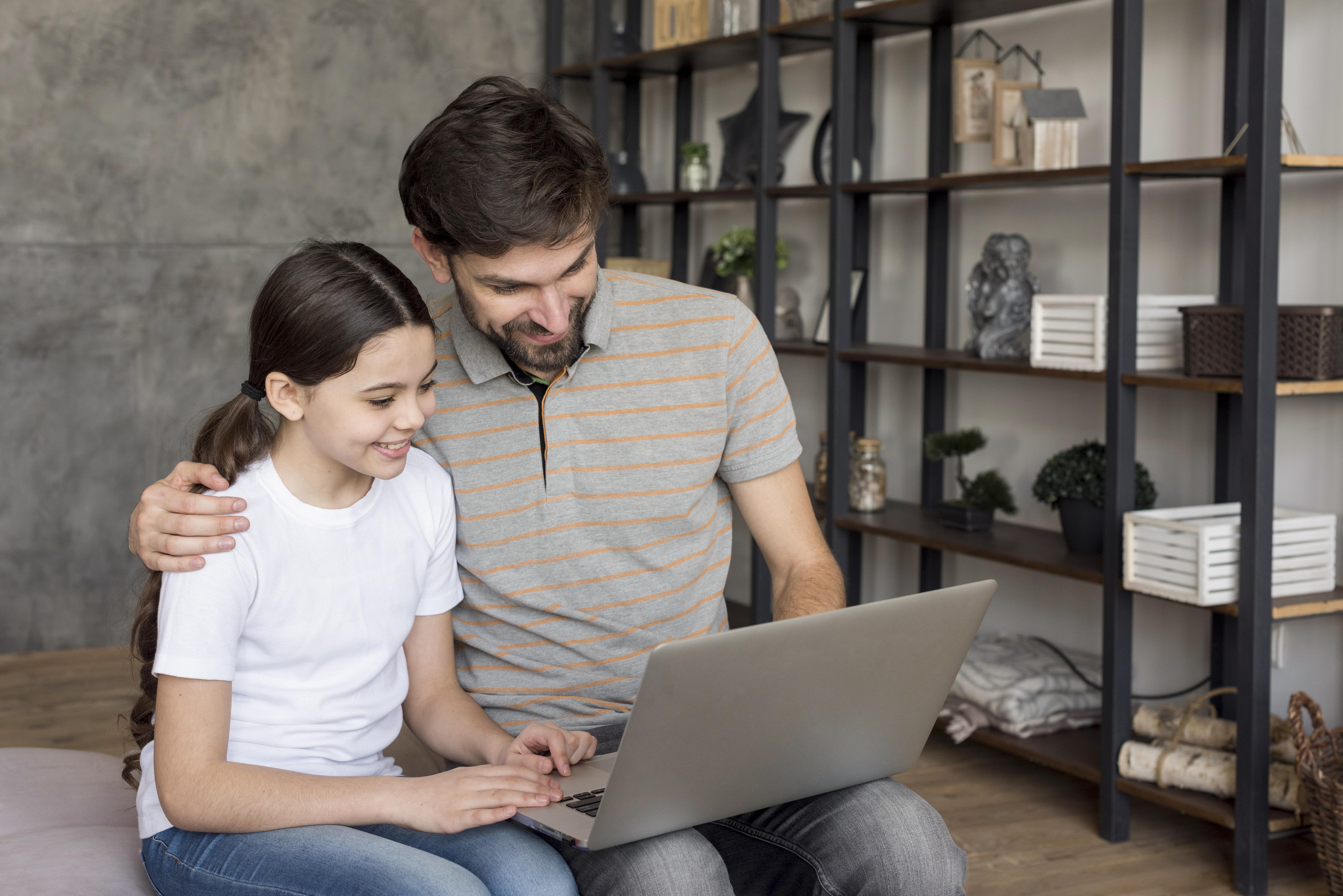 Una niña y su padre usando un portátil | Fuente: Freepik