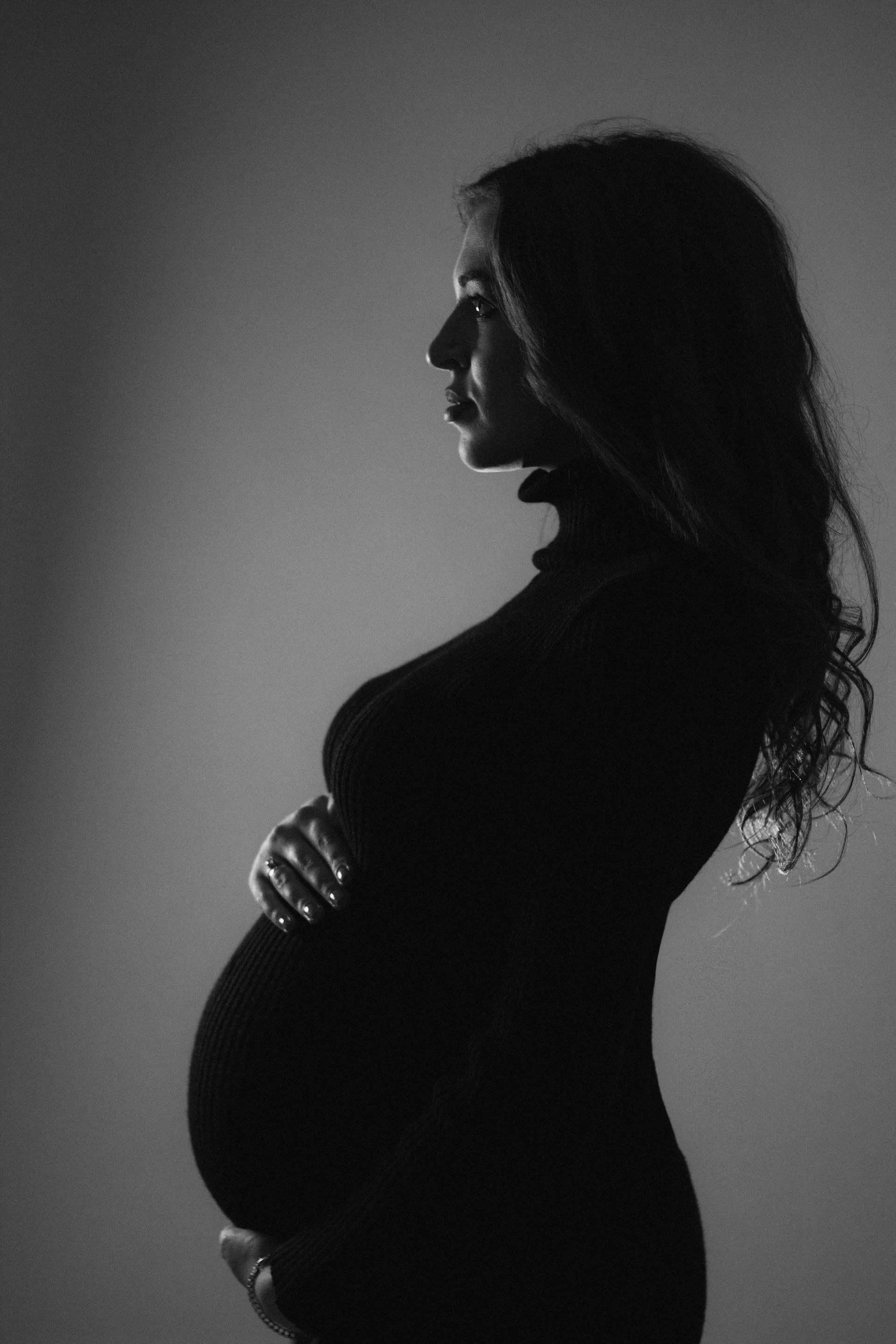 Imagen de perfil en blanco y negro de una mujer embarazada sujetando su barriguita | Fuente: Pexels