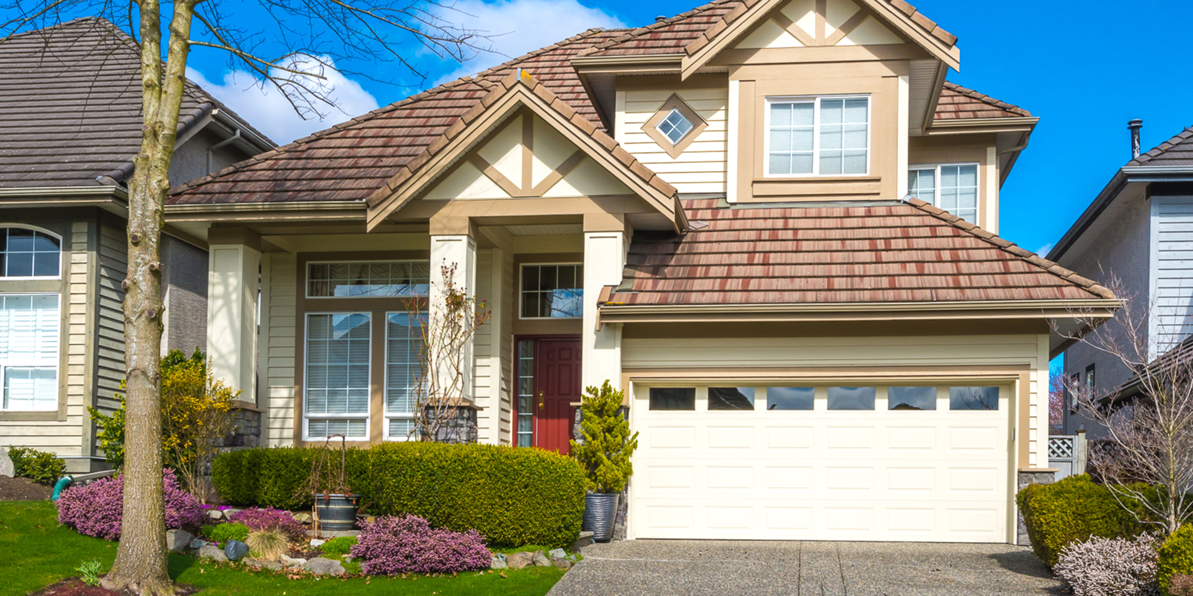 Una casa suburbana con una puerta de entrada roja, un jardín cuidado y un exterior luminoso y acogedor | Fuente: Shutterstock