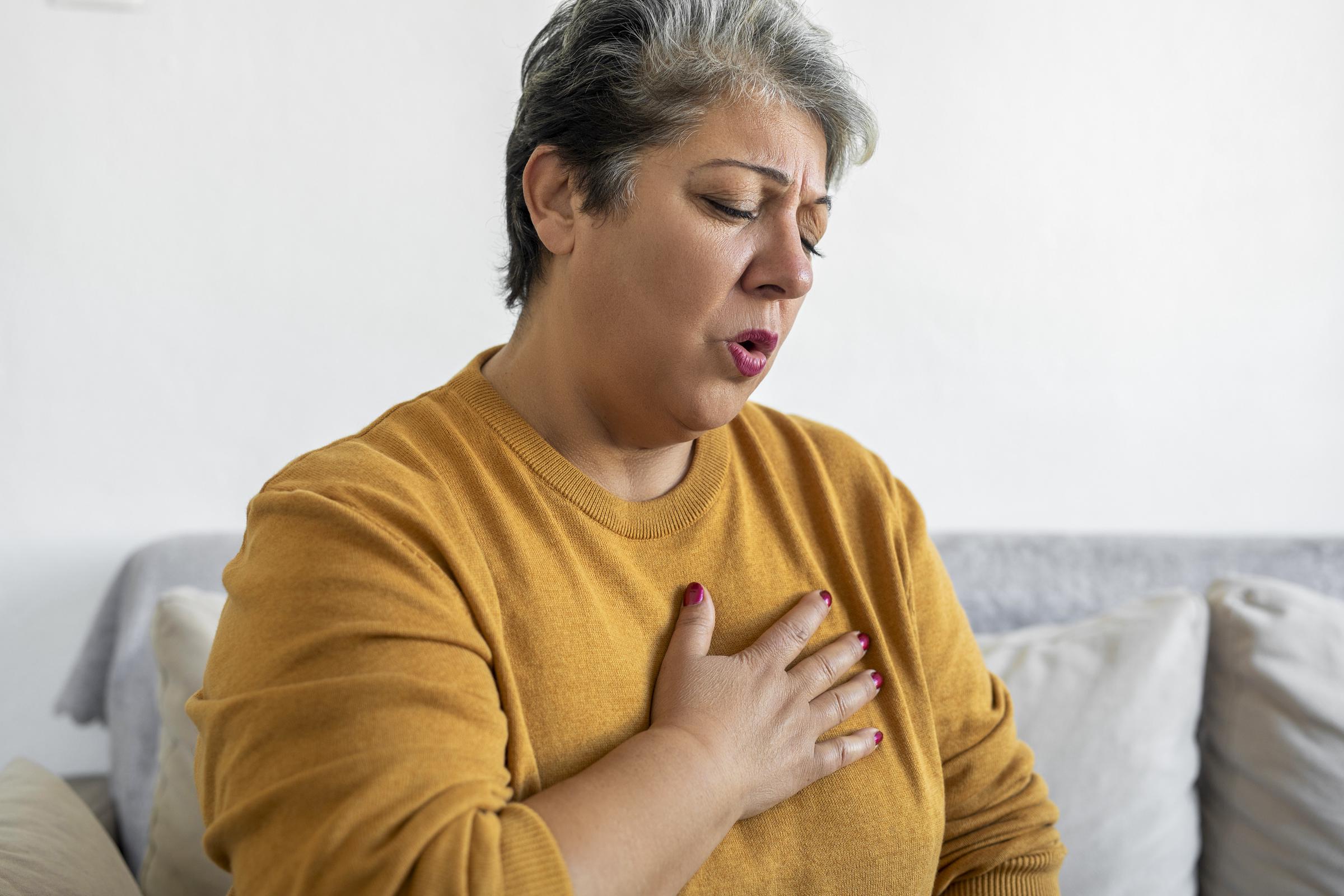 Mujer agarrándose el pecho, experimentando dolor y dificultad para respirar | Fuente: Getty Images