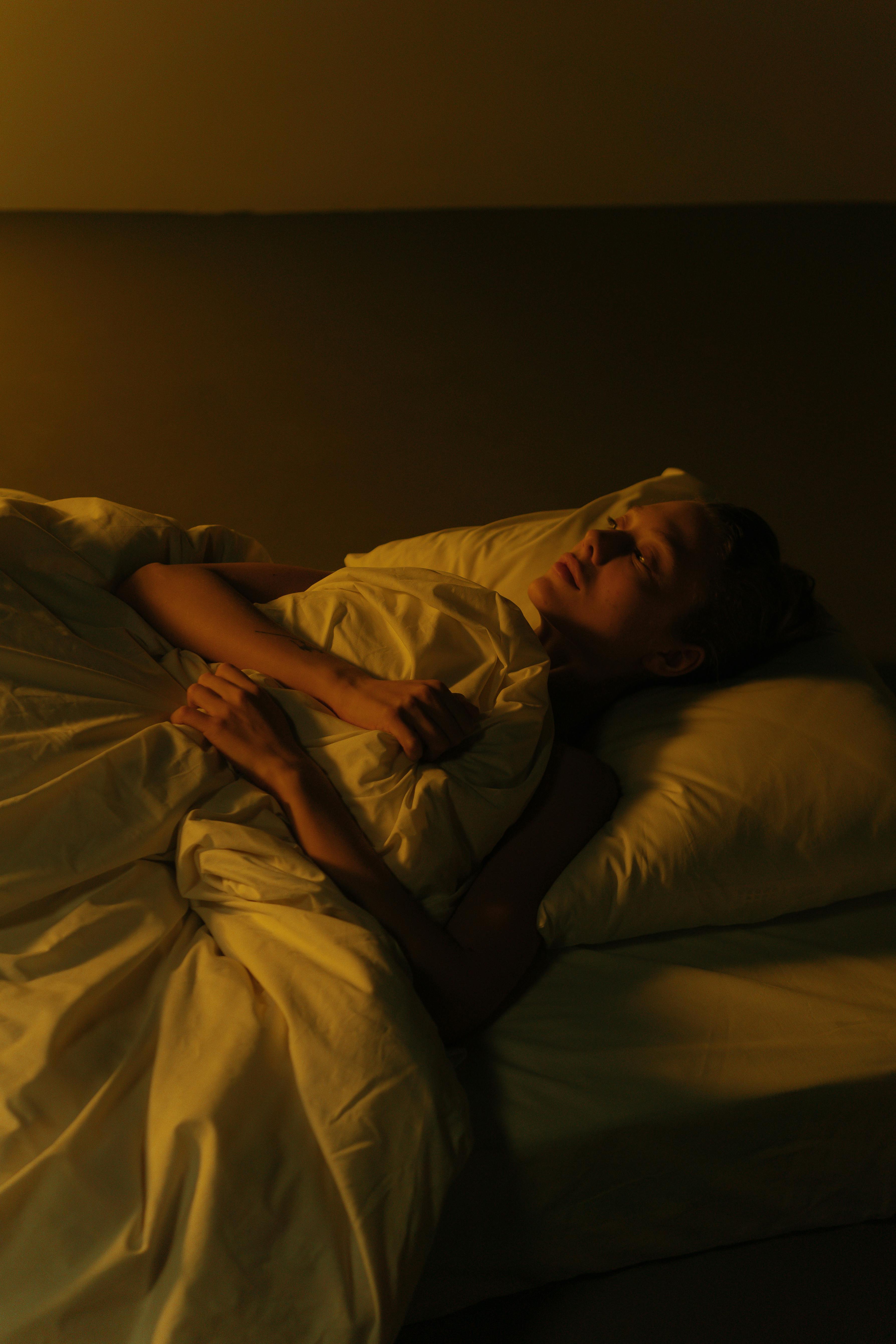Una mujer triste tumbada en la cama | Fuente: Pexels