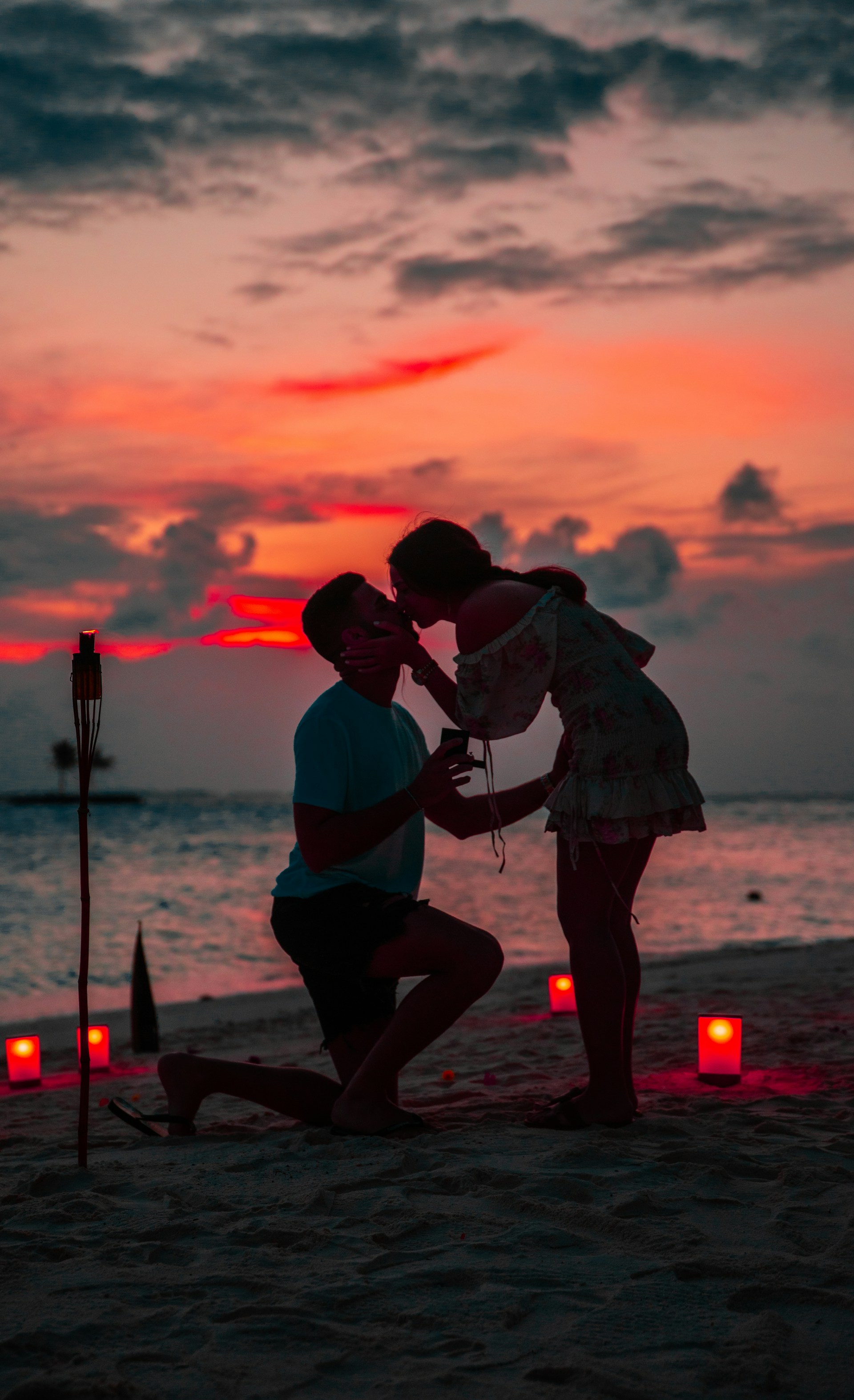 Un hombre arrodillado con un anillo mientras su pareja le besa | Fuente: Unsplash