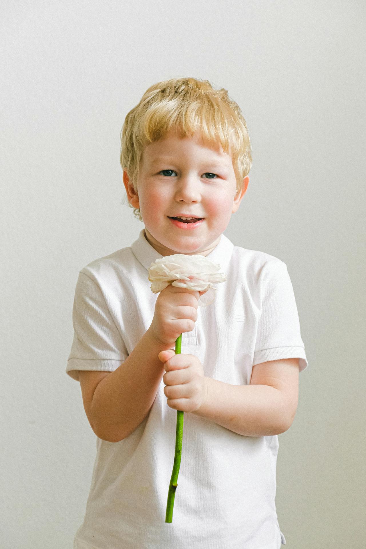 Un niño emocionado sujetando una flor | Fuente: Pexels