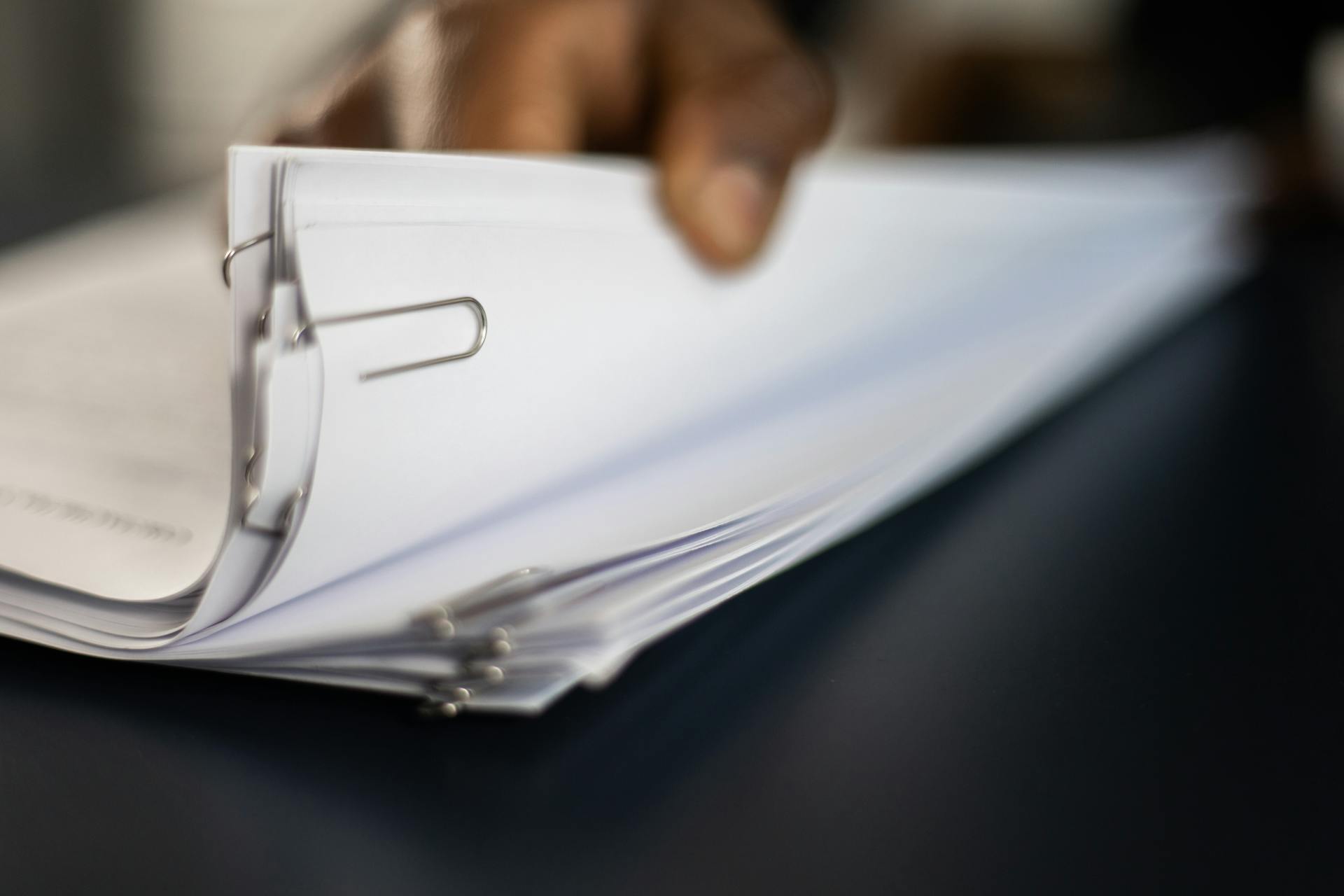 Una persona sostiene una pila de documentos clavados | Fuente: Pexels