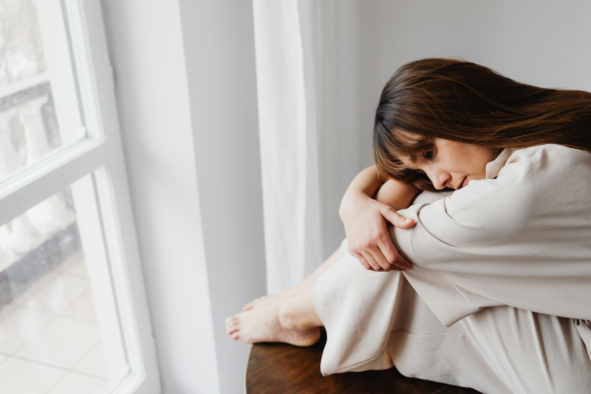 Una mujer angustiada sentada junto a la ventana | Fuente: Pexels