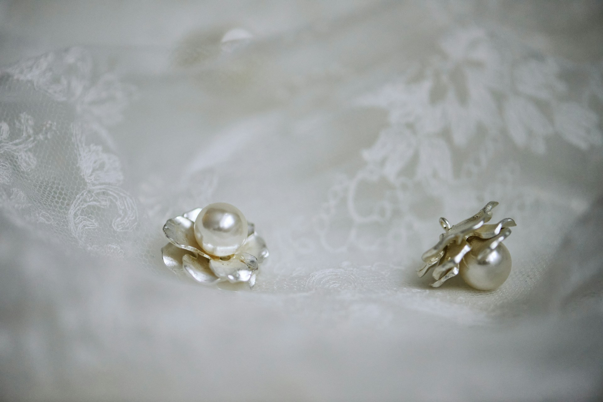 Un par de pendientes de perlas sobre una tela de encaje | Fuente: Unsplash