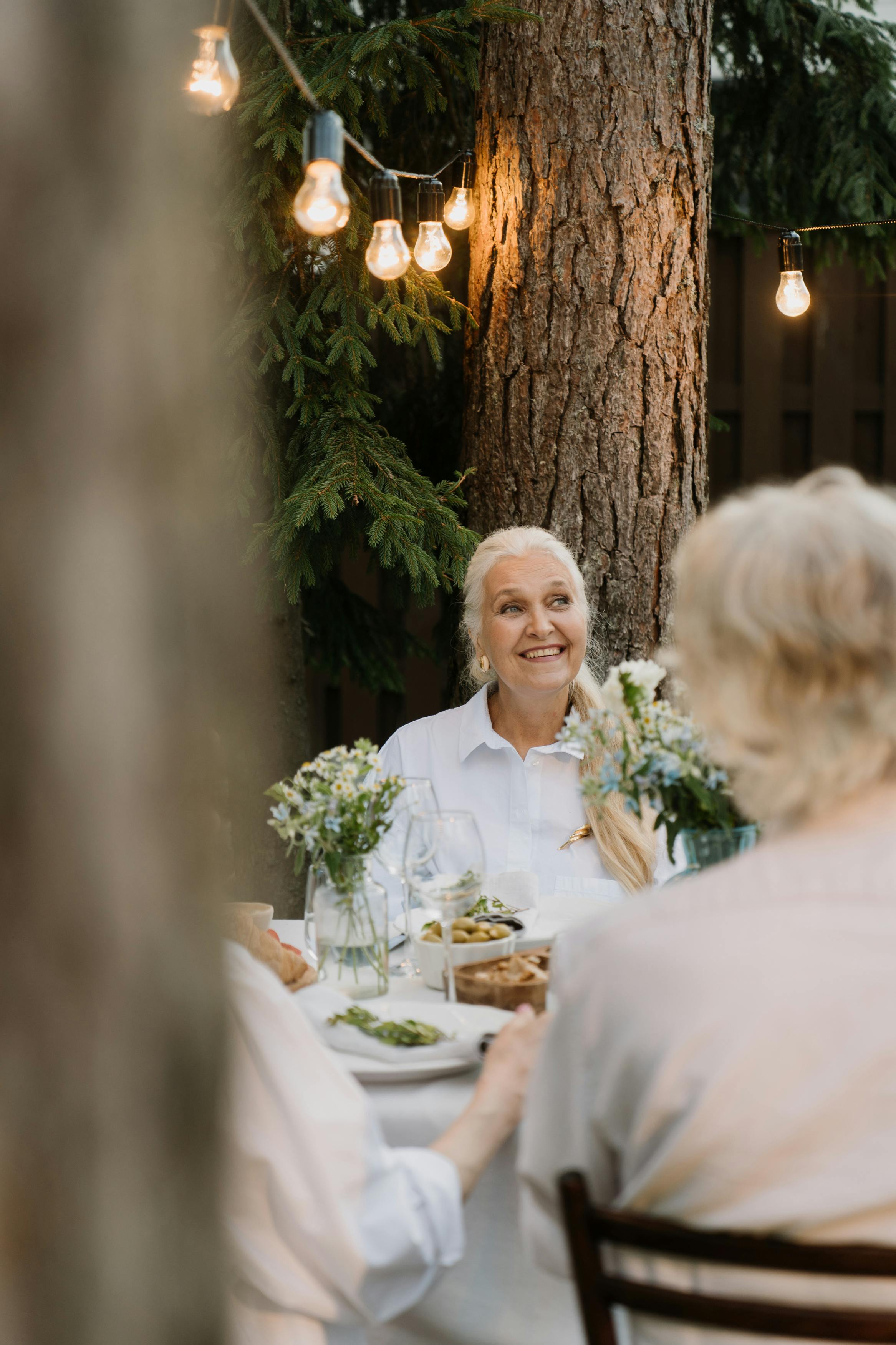 Una mujer feliz disfrutando de una comida con otras personas | Fuente: Pexels
