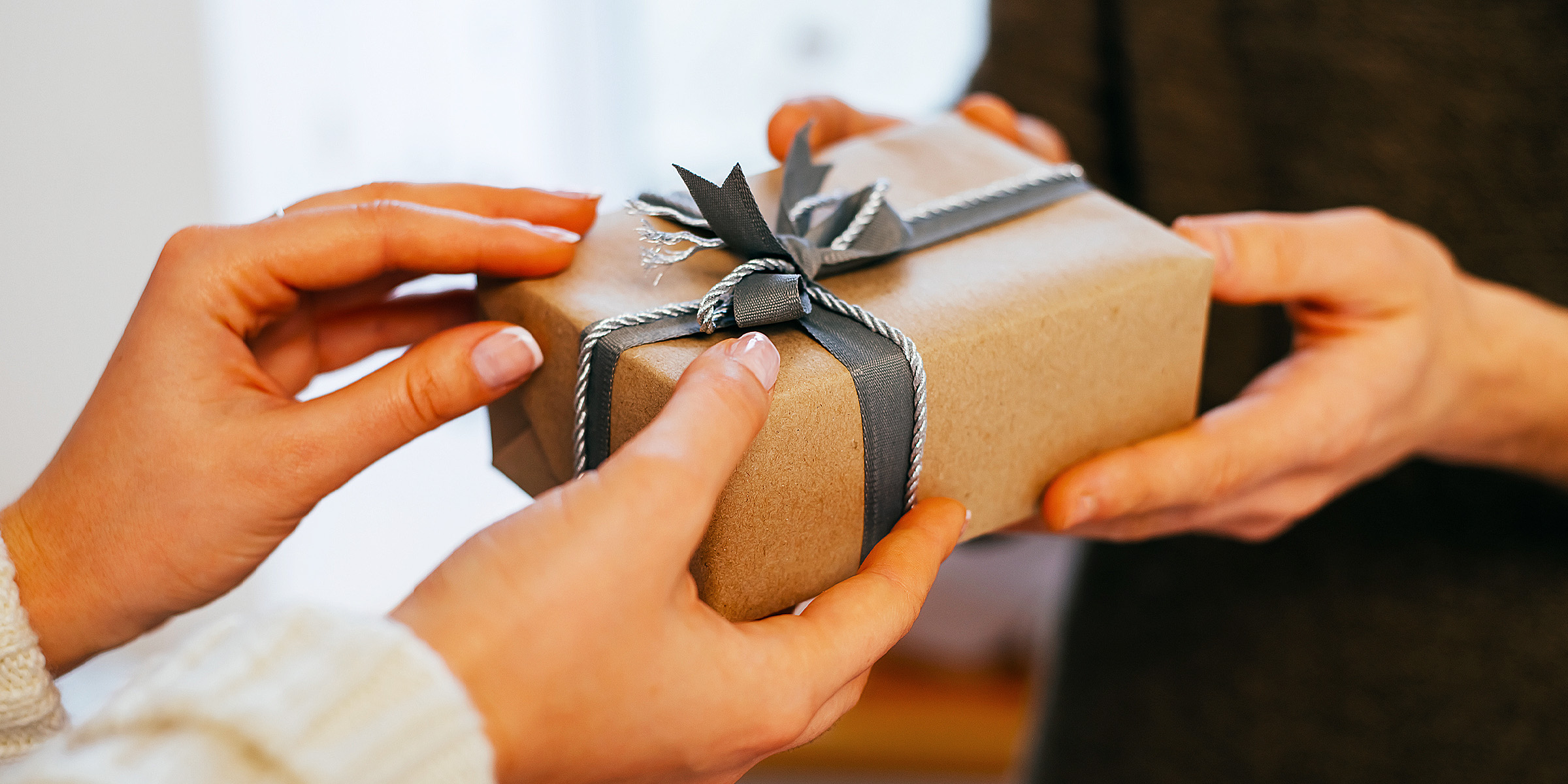 Dos personas sosteniendo una caja de regalo | Fuente: Shutterstock