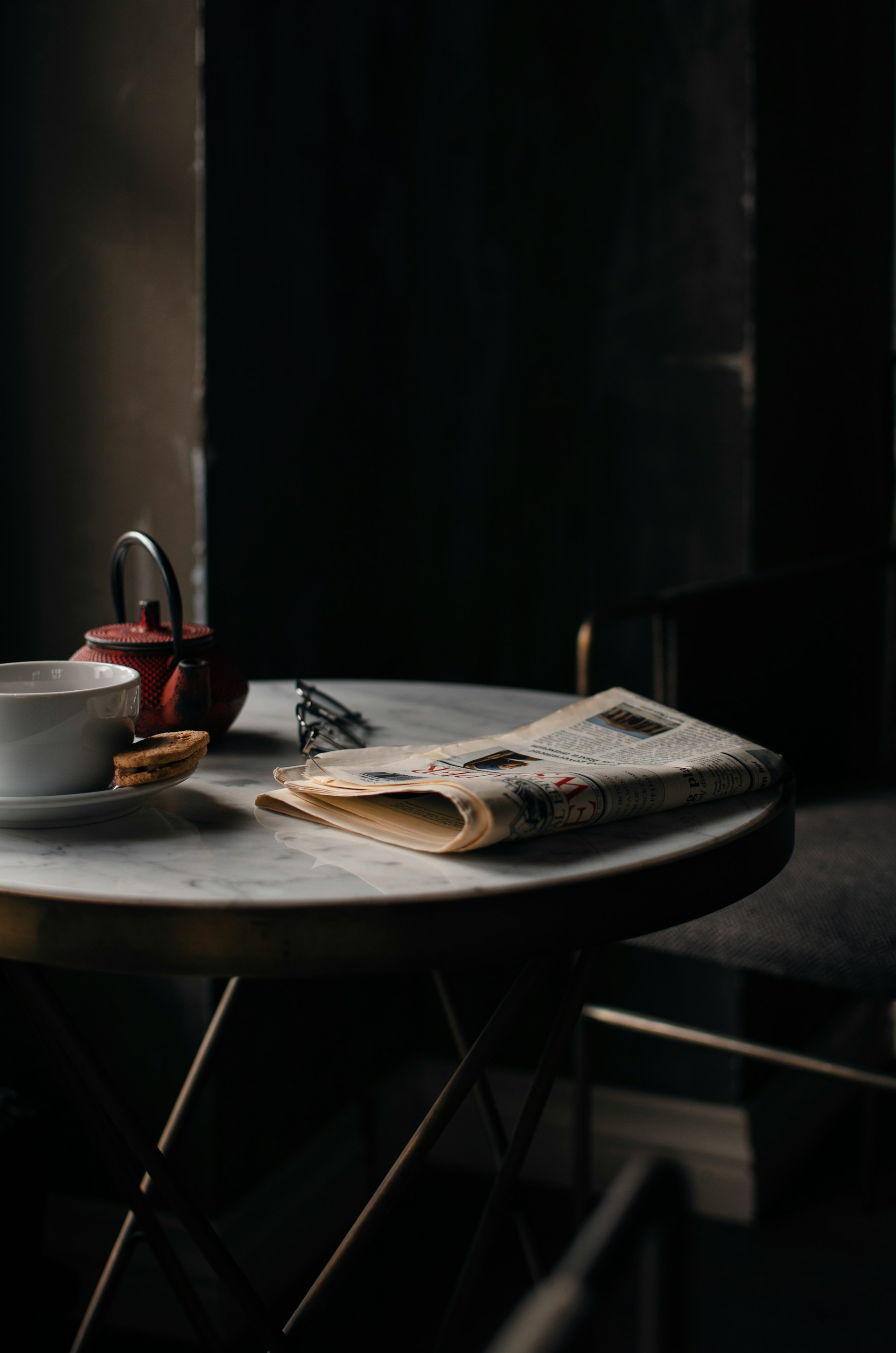 Una tetera y una taza de café junto a un periódico bien doblado | Fuente: Unsplash