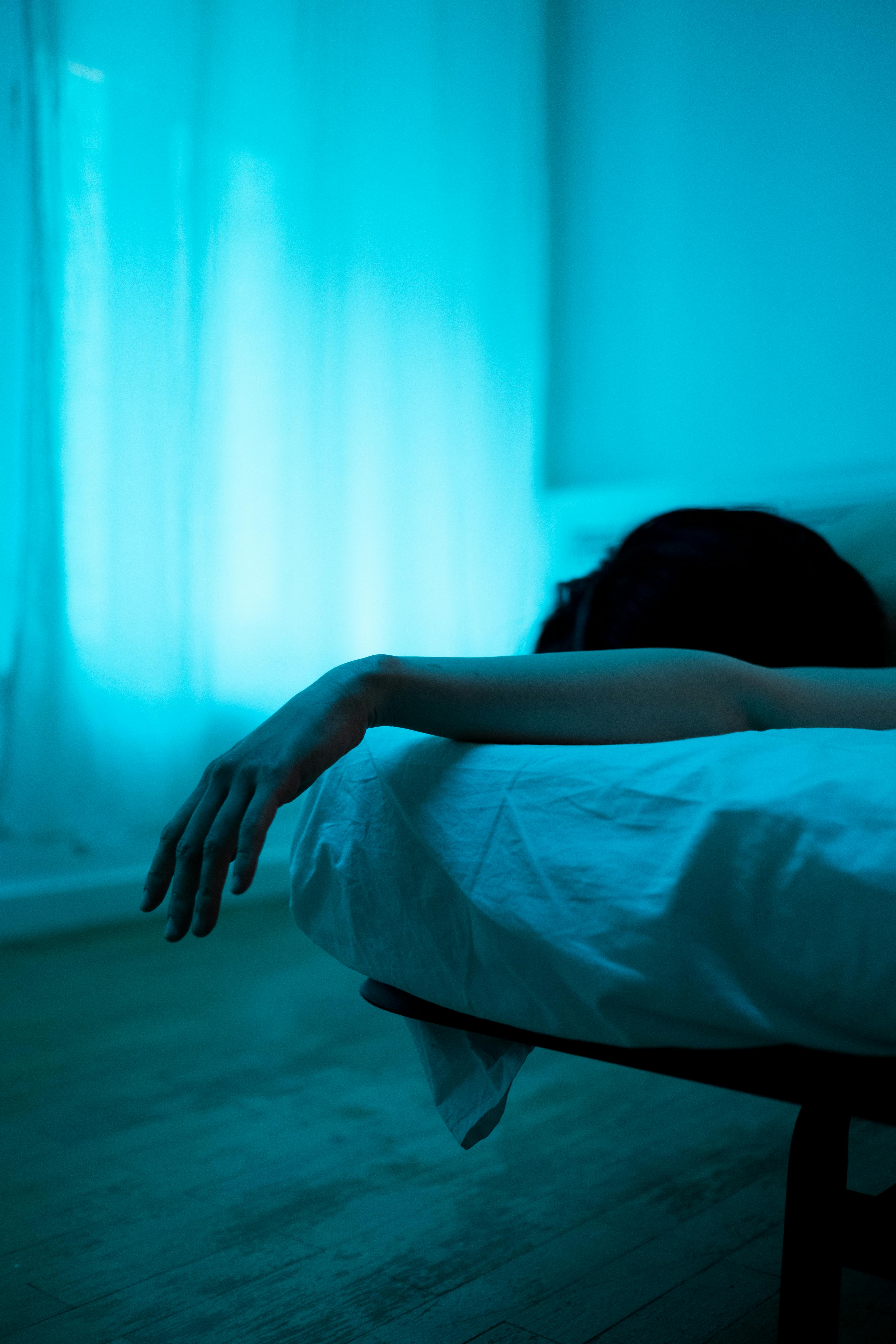 Una mujer tumbada en la cama en la oscuridad | Fuente: Pexels