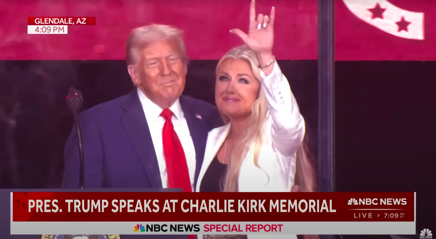 Erika Kirk haciendo la señal con la mano mientras Donald Trump mira. | Fuente: YouTube/NBC News