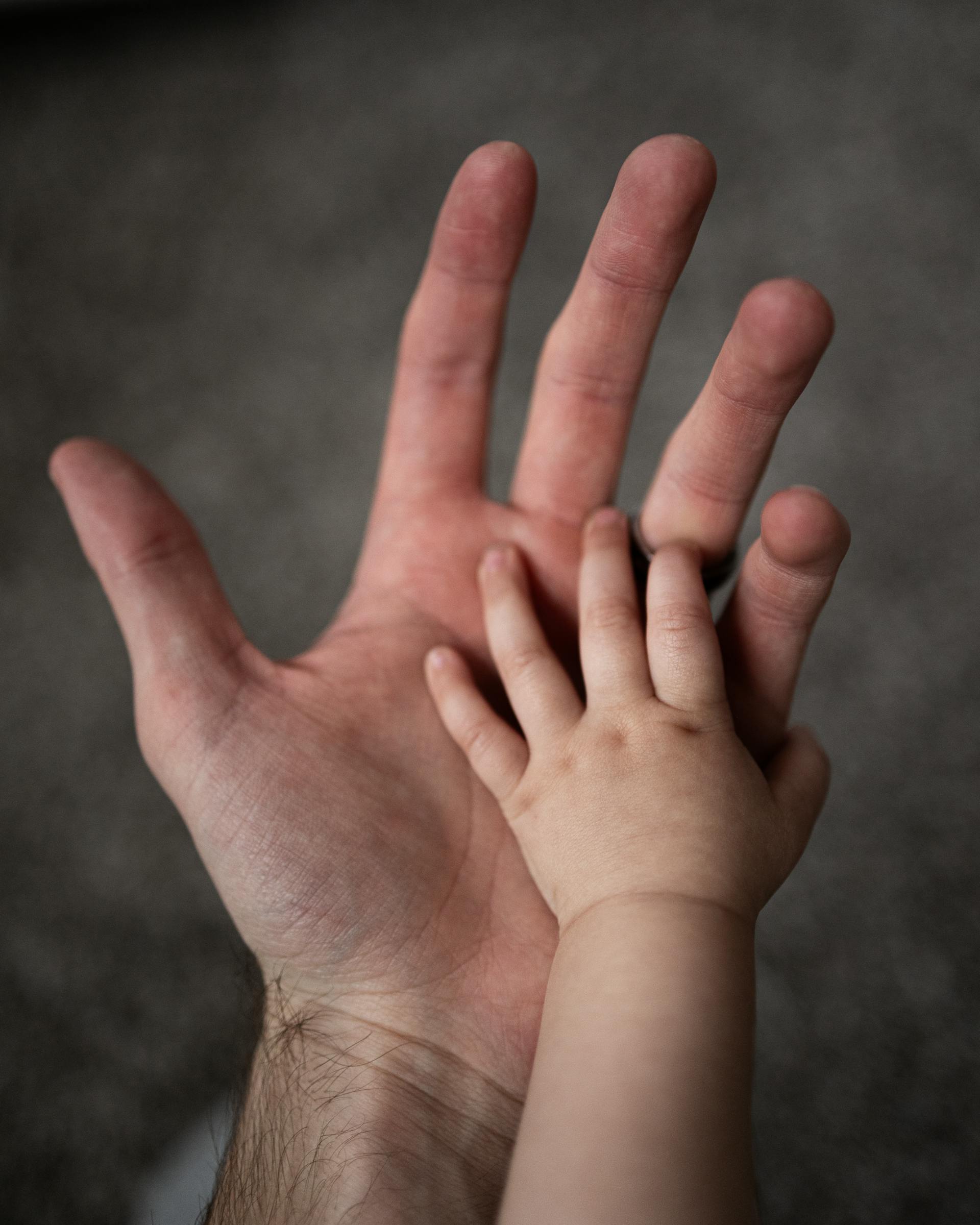 Las manos de un hombre y un bebé | Fuente: Pexels
