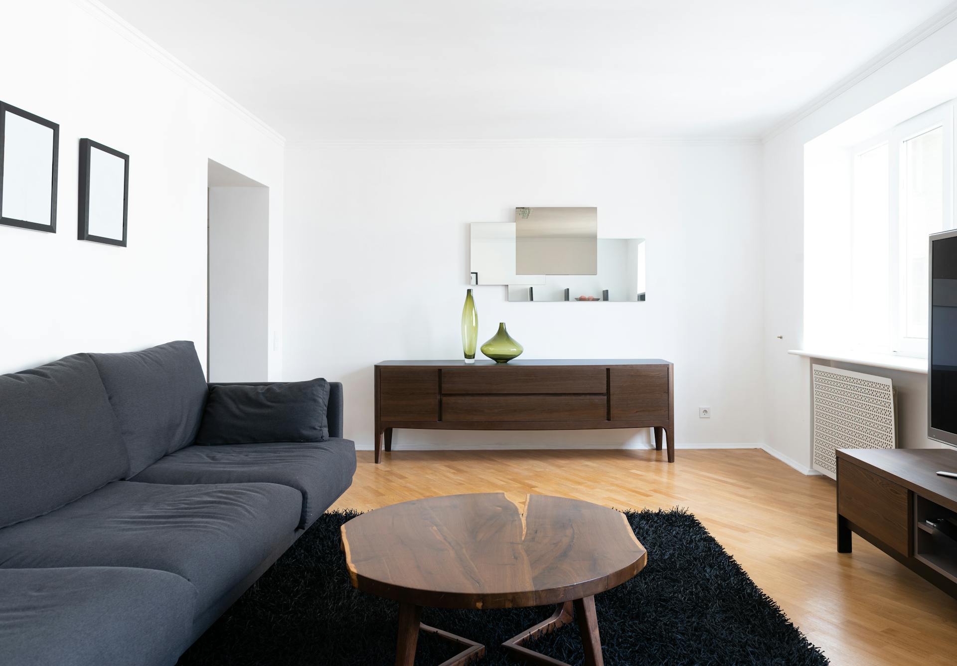 Un salón limpio con un sofá negro, una mesa de centro de madera y un armario marrón | Fuente: Pexels