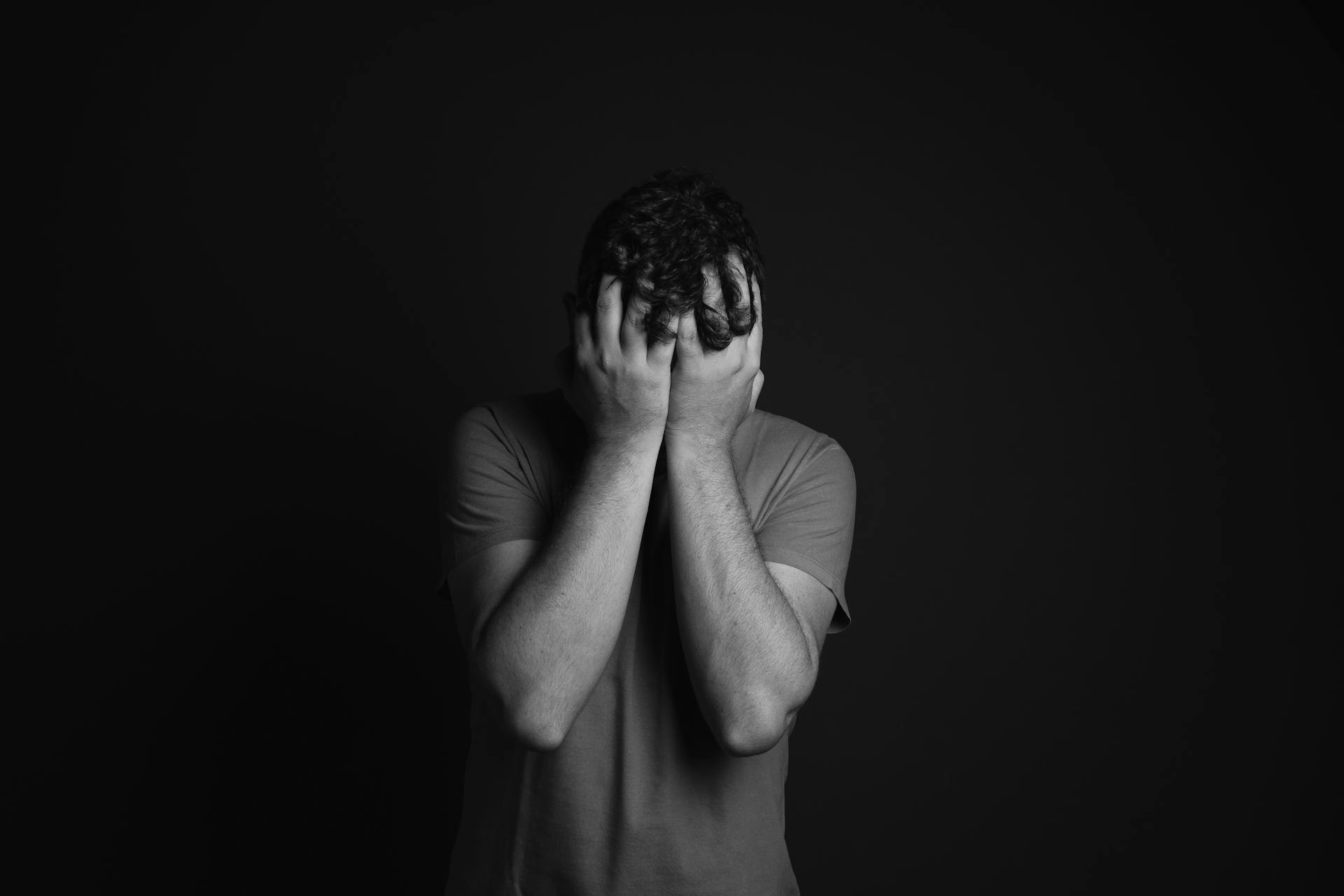 Un hombre de pie con las manos en la cara | Fuente: Pexels