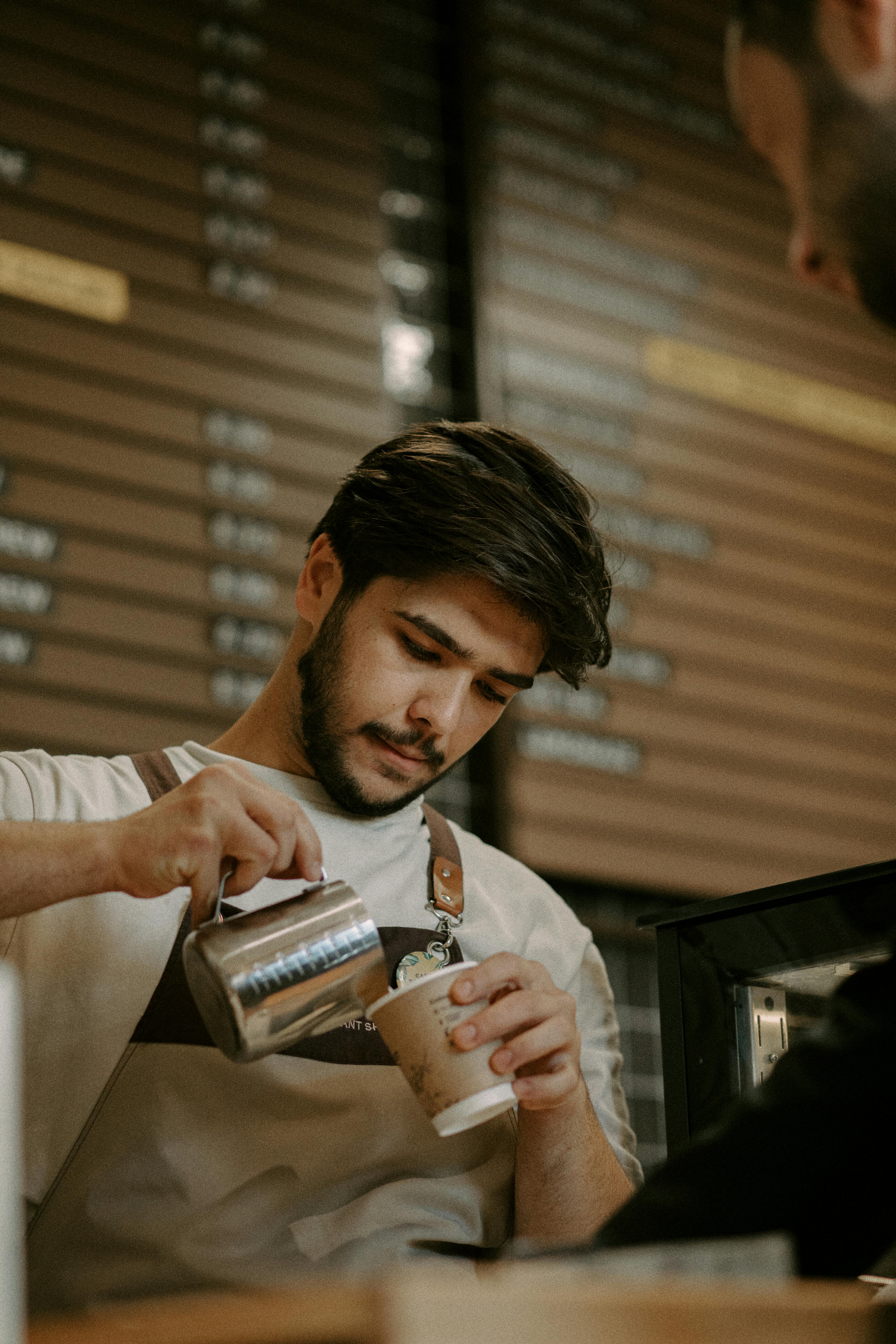 Barista vertiendo leche en el café | Fuente: Pexels
