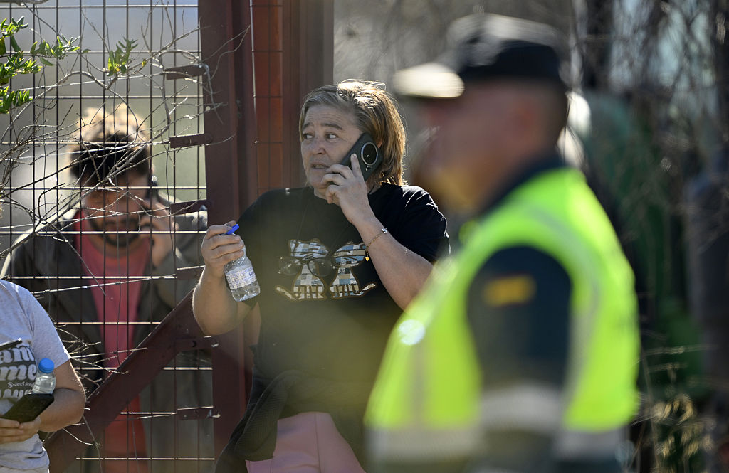 Personas realizan llamadas mientras los equipos de emergencia trabajan en el lugar de una colisión en la que se vieron involucrados dos trenes de alta velocidad, cerca de la estación de Urda, en la provincia de Toledo (España), el 28 de octubre de 2026. | Fuente: Getty Images